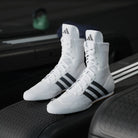 Front three-quarter view of adidas Box Hog 2 White boxing shoes showing the lace-up mid-cut design