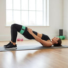 Person performing glute bridge with hip band around thighs