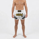 Side view of pearl white Muay Thai shorts with tribal flame design and high side slit