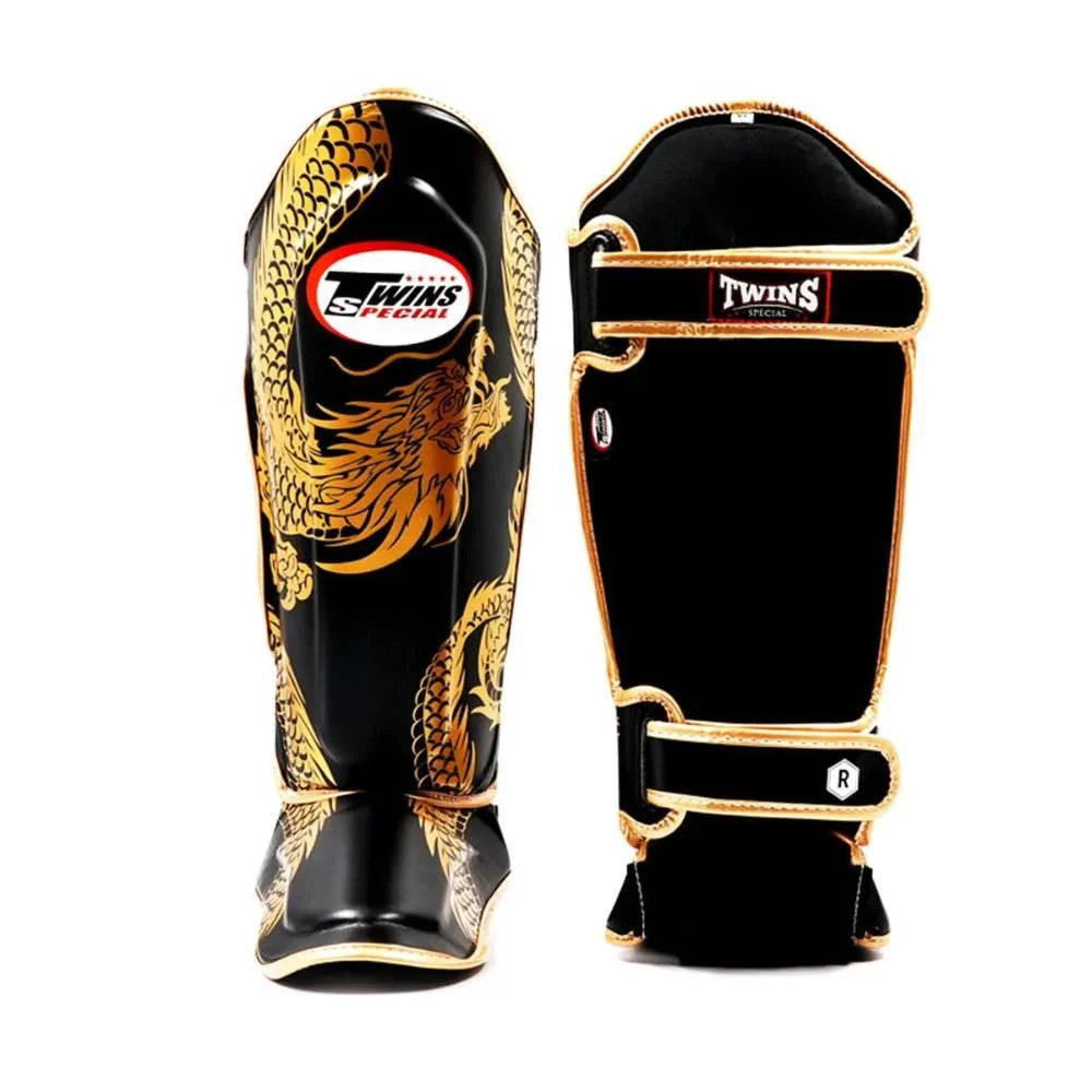 Twins Dragon Black/Gold leather shin guards shown from the front and rear with dragon artwork and adjustable strap layout visible