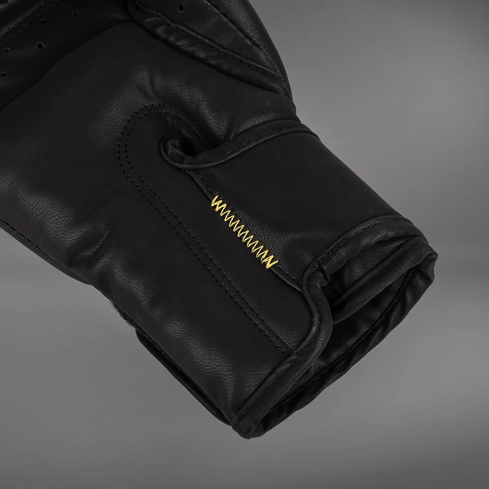 Close-up of the Venum Serpenti boxing glove cuff and palm area showing black PU construction and contrasting gold stitching
