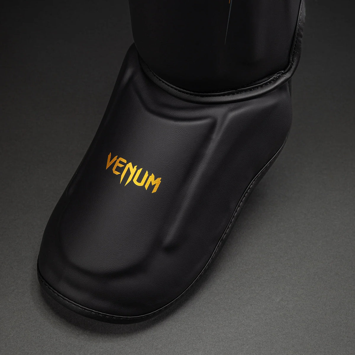 Black/Gold Venum Streamline shin guard product view highlighting the instep section and gold branding